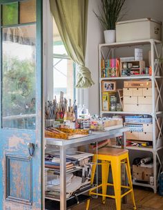 an open door leading into a room with lots of crafting supplies on the table