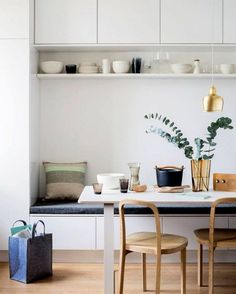 a kitchen with white cabinets and wooden flooring, along with a dining table surrounded by chairs