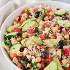 a salad with cucumbers, tomatoes, black olives and tuna