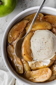 a bowl filled with bananas and ice cream on top of a white table next to an apple