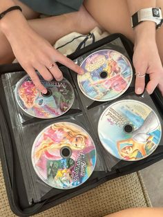 a woman sitting on the floor with four dvds in her lap and one is pointing at it