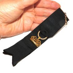 An Edwardian black ribbon watch fob with a tested 14 K ornate seal. The ribbon is folded over and sewn onto a gold-filled hanger which is attached to a gold-filled watch hook via a short chain. The gold seal is hanging on a hollow ring sewn into the fold of the ribbon. The ornate seal has a scrolled top and engraved initials on the bottom -EAC. Everything is in excellent condition. The total length of the fob, from the hook to the end of the ribbon is 18 cm. The seal itself is 2.6 cm wide. A good accessory for the collector of antique watches! Classic Formal Jewelry With Brass Hardware, Gold Ribbon Jewelry For Formal Occasions, Elegant Gold Jewelry For Black Tie Event, Elegant Gold Jewelry For Black Tie, Black Jewelry With Gold Clasp For Formal Occasions, Formal Black Jewelry With Black Ribbon, Vintage Gold Jewelry With Ribbon, Elegant Black Jewelry With Gold Clasp, Hollow Ring