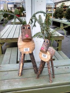 two small wooden animals sitting on top of a bench next to each other with plants growing out of them