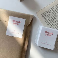 two thank you cards sitting on top of an open book