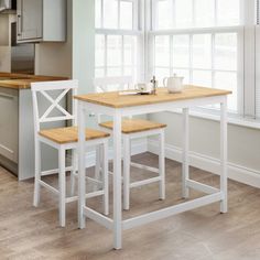 a kitchen table and two stools in front of a window