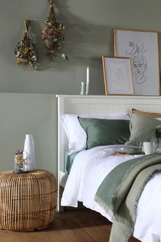 a bed with white sheets and green pillows