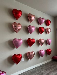 many heart shaped balloons are hanging on the wall