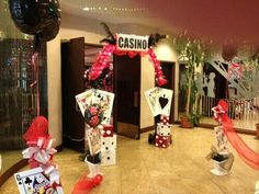 a casino themed party with red and black decorations, cards, streamers and balloons