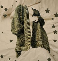 two crocheted sweaters laying on top of a bed with stars in the background