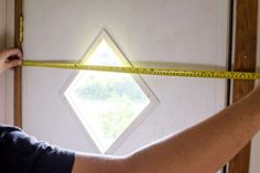 a man measuring the height of a door with a tape measure on it's side