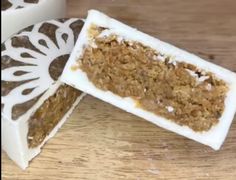 two pieces of cake sitting on top of a wooden table with white frosting and decorative designs