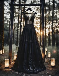 a dress hanging on a wooden frame in the woods with lit candles around it and an open - air canopy