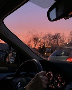 the sun is setting behind some cars in traffic