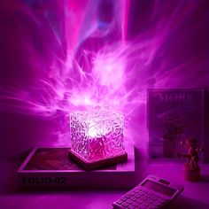 a cell phone sitting on top of a table next to a purple light cube lamp