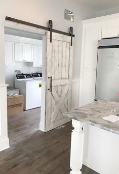 a kitchen with an open barn door and white cabinets