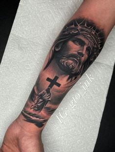 a man's arm with a cross and jesus on the cross tattoo in black ink