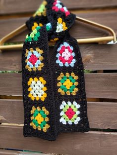 a crocheted scarf hanging on a clothes hanger in front of a wooden bench