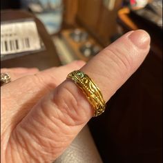 a close up of a person's hand with a gold ring on their finger