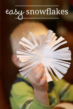 a young boy holding up a paper snowflakes in front of his face with the words easy snowflakes on it