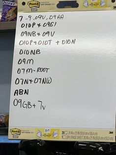 a white board with writing on it in front of a store display shelf filled with items