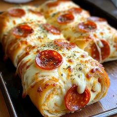 two pepperoni pizzas sitting on top of a baking pan covered in cheese and sauce