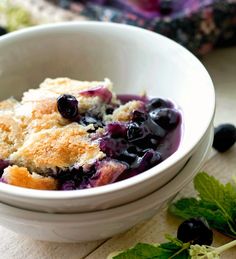 blueberry pudding cake in a white bowl with green leaves on the side and text overlay