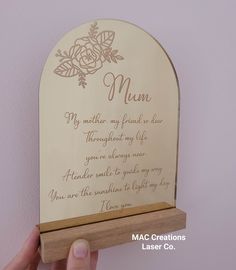 a person holding up a wooden plaque with writing on it that reads mum, mother my friend is in law