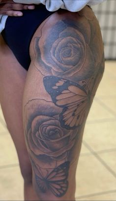 a close up of a person's thigh with tattoos on it and flowers in the background