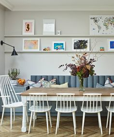 a dining room table with white chairs and pictures on the wall