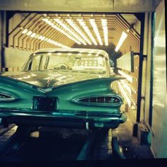 an old car is being worked on in a garage with lights shining from the ceiling