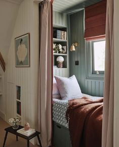 a bed sitting under a window next to a book shelf with books on top of it