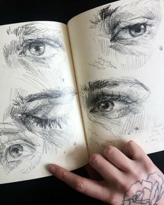 a person's hand holding an open book with drawings on the inside of it