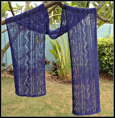 two blue crocheted shawls hanging from a tree