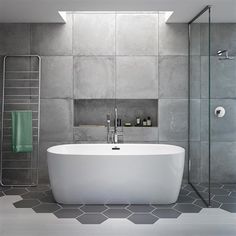 a bathroom with a white bath tub sitting next to a walk in shower and tiled walls