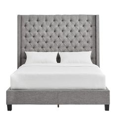 an upholstered bed with white sheets and pillows