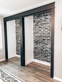 an empty room with brick walls and wood flooring in the corner, along with a white rug