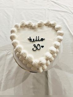 a heart shaped cake with the word hello 30 written in black on it's frosting