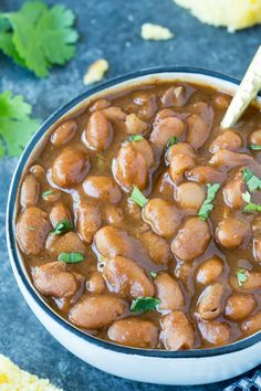 a bowl filled with beans and cilantro on top of a blue table cloth