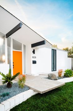 a modern house with white walls and orange door