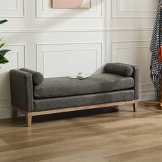 a gray chaise lounger sitting on top of a hard wood floor next to a potted plant