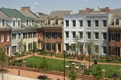 a row of multi - colored townhouses in the middle of an urban park area