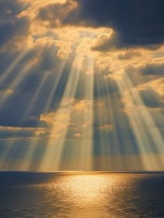 the sun is shining through clouds over the ocean