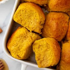 a white casserole dish filled with cornbread muffins and cinnamon sticks