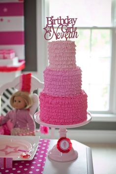 a pink and white birthday cake sitting on top of a table