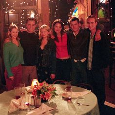 a group of people standing in front of a table with food and drinks on it