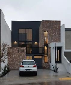 a white car parked in front of a house on a wet parking lot with stairs leading up to it