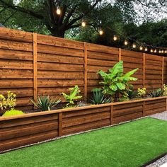 a wooden fence with plants and lights hanging from it's sides, along with artificial grass