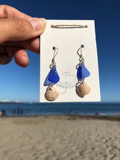 "Blue sea glass & shell dangle earrings! Here is your daily Vitamin Sea 💙 May the beach be with you! Go and wear the beach with this dangle sea glass & shell hook earrings whenever you need to feel the sea! I love to find the matching pairs for the earrings, as every piece is unique there will always be a tiny difference between the matching pair of sea glass / shells.  I do my very best to find the best matching pairs for all of my earrings. Keep in mind that all my sea glass pieces are shaped by nature, or as I say \"designed by the sea\", this unique shapes make them even more likable. YOU'LL GET WHAT YOU SEE <3 ! The necklace and the other earrings samples in the pictures are NOT included in this offer, you can order them separately if interested ! You will receive exactly this pair o Beach Earrings With Recycled Glass And Ear Wire, Blue Shell-shaped Earrings For Beach, Beach Earrings With Sea Glass And Ear Wire, Beach Sea Glass Earrings With Ear Wire, Sea Glass Teardrop Earrings For Beach, Sea Earrings, Daily Vitamin, Matching Pairs, Ocean Jewelry