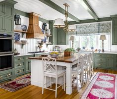 a large kitchen with green cabinets and white counter tops, an area rug on the floor