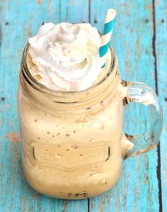 a glass mug filled with whipped cream on top of a blue table